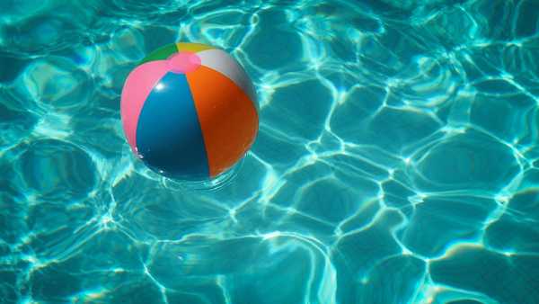 Beach ball in shimmering pool water during daytime hours